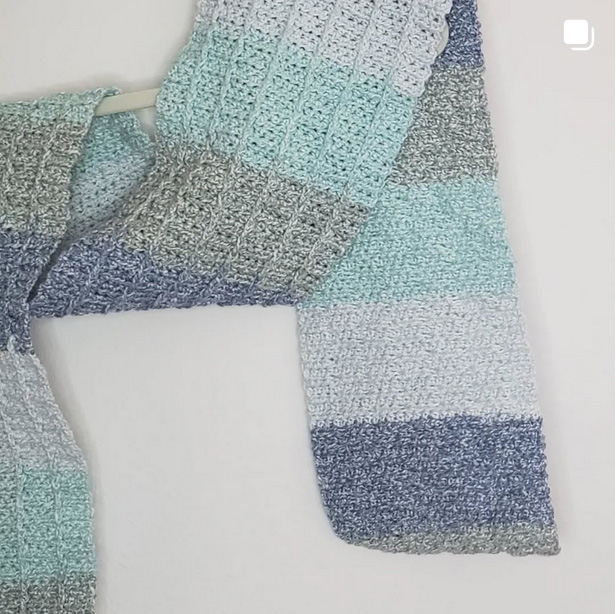 a light blue and seafoam green scarf wrapped on a hanger